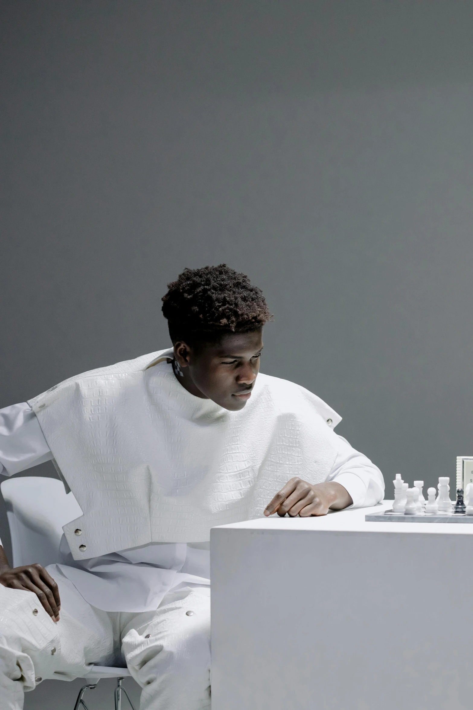 a man playing chess in a white room