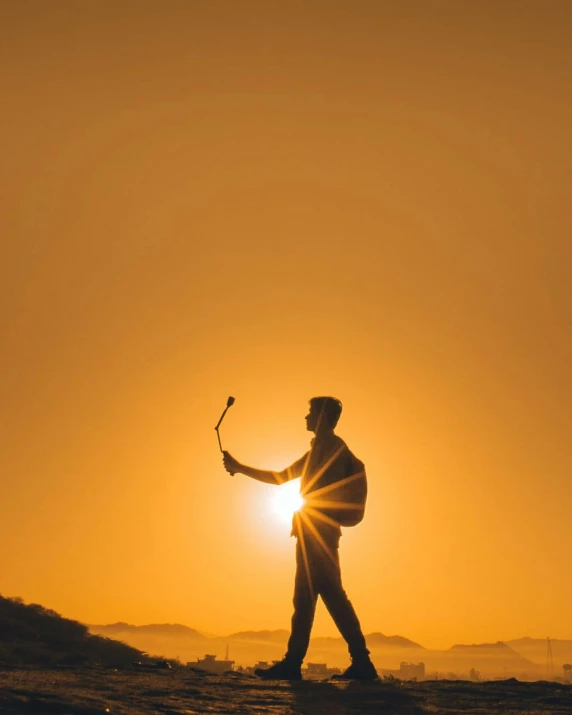 the sun is setting behind a man with an umbrella