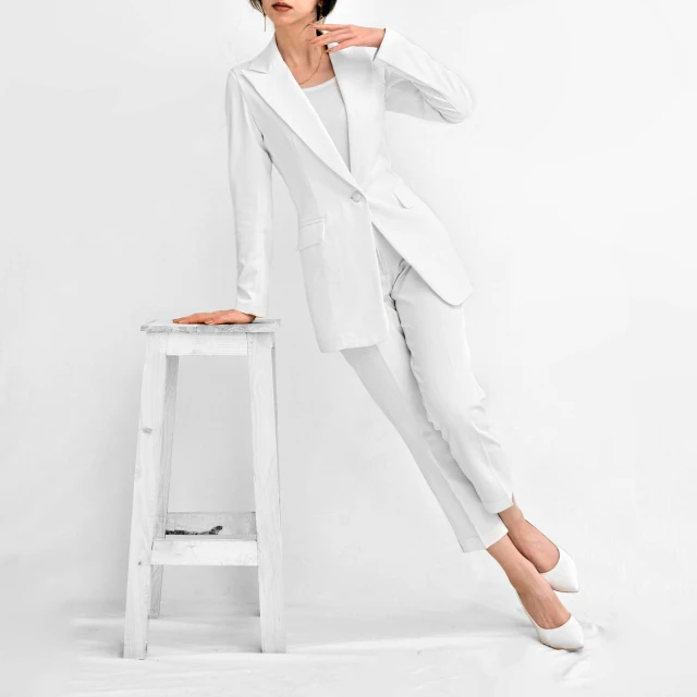 a woman wearing a white suit standing on a stool