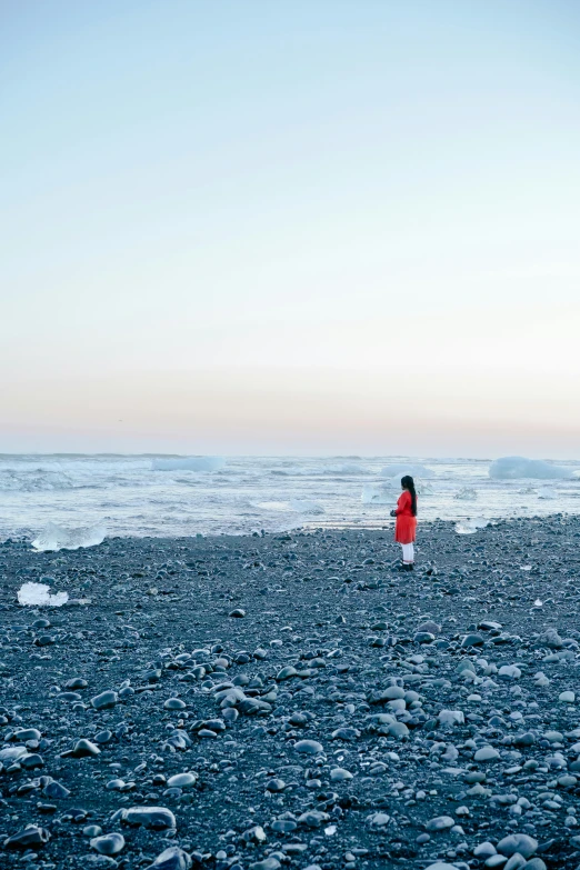 a woman is standing on a beach and looking at the water