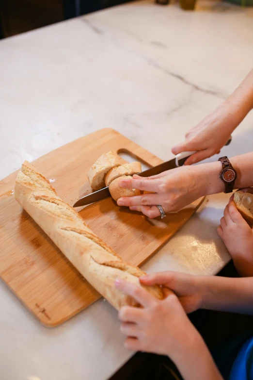two women are using scissors to cut some bread