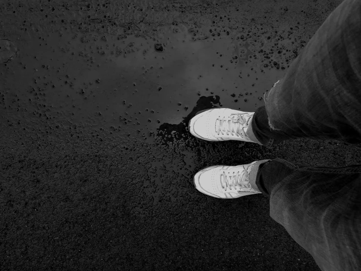 someone's legs in white shoes on black sand