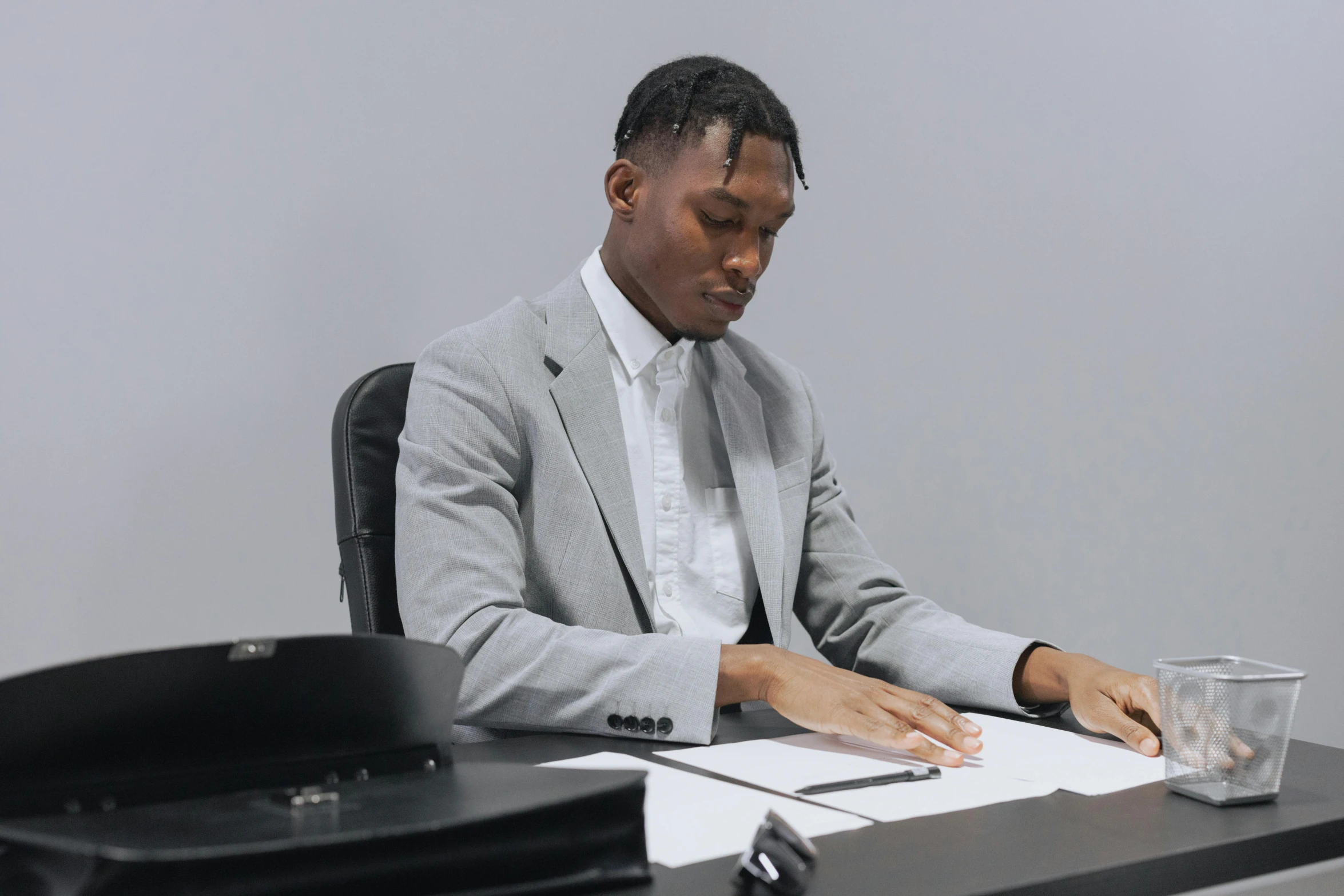 a young man in suit sitting at a desk writing