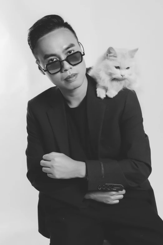 a man in sunglasses leaning on his arm with a white cat sitting on his shoulders