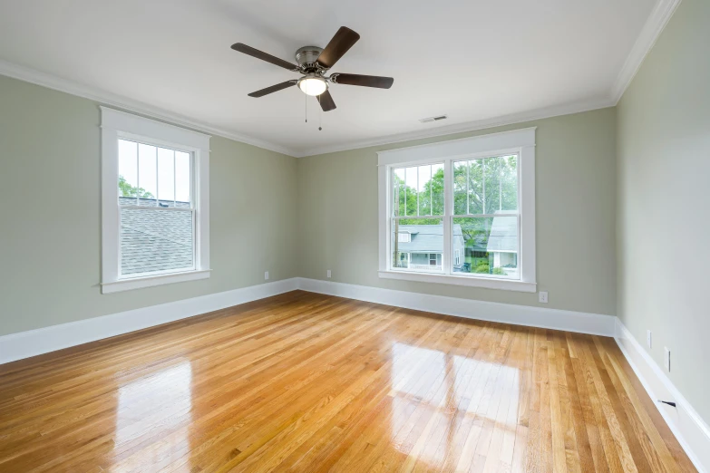 an empty room with wood floors and two windows