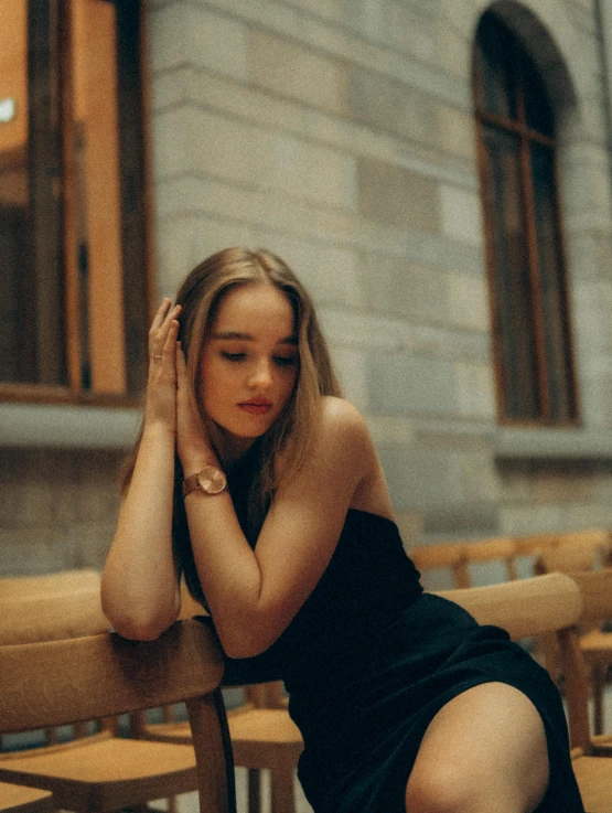 a young woman sitting on a bench in front of a building