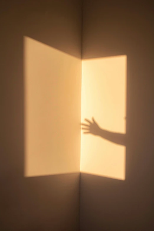 a hand casts a shadow of a folded square wall