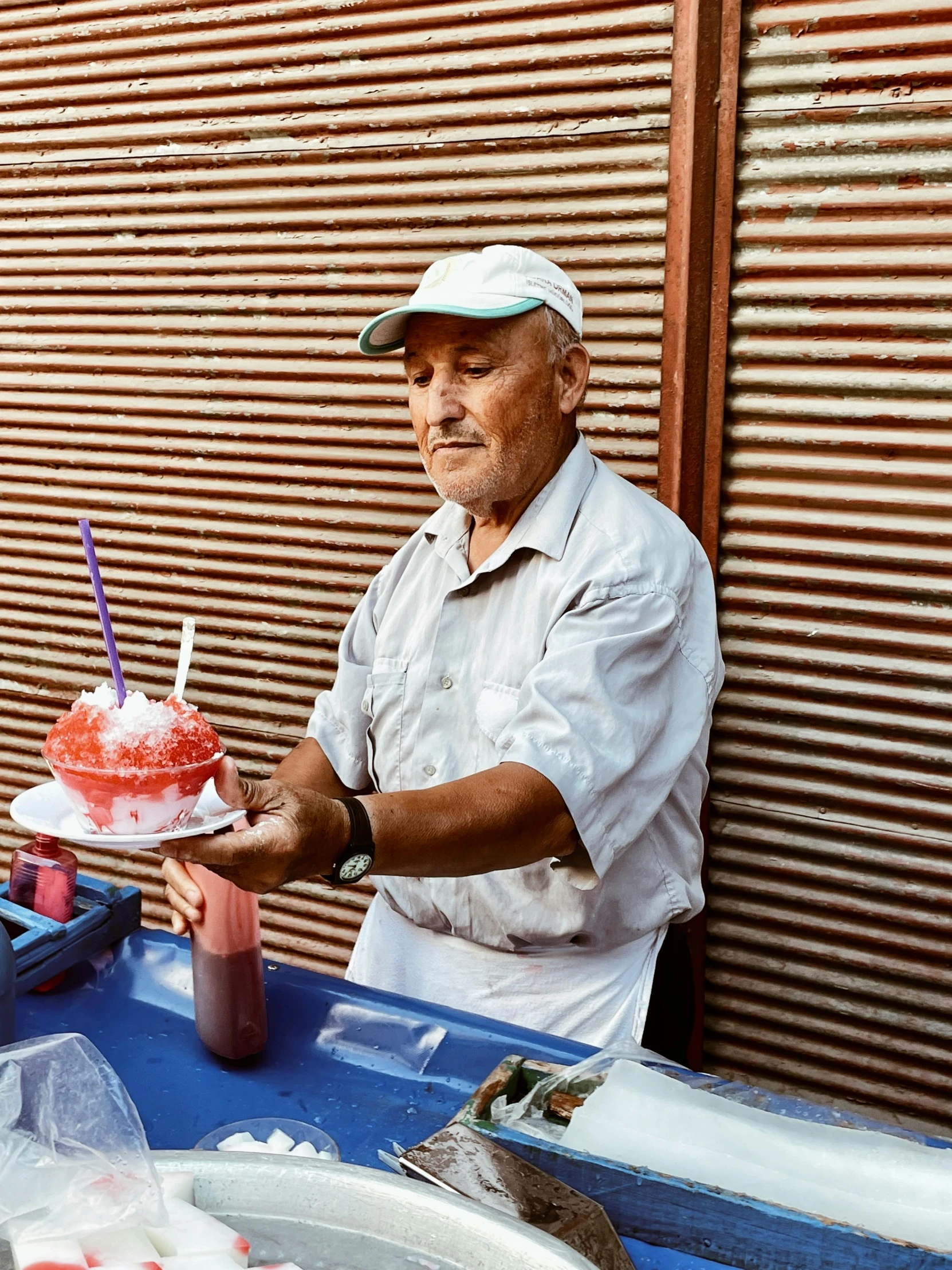 a man wearing white holds a cake that is red