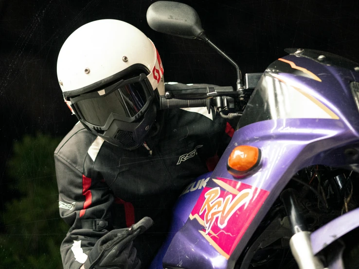 man in black motorcycle suit and helmet looking behind the front wheel