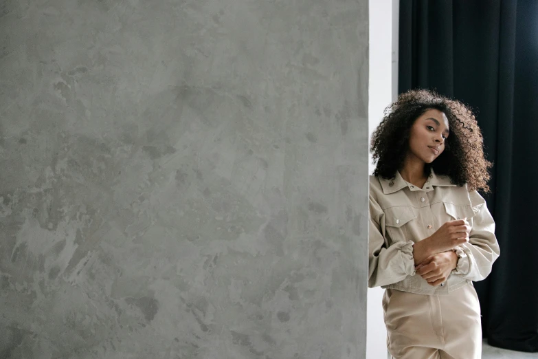 a woman standing next to a white wall