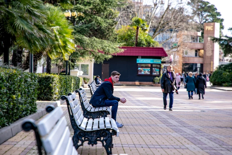 man sitting on a bench next to others in a city