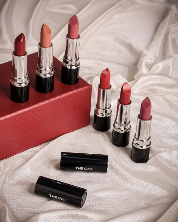 a pink box with six lipsticks sitting on a bed