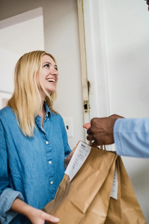 two women shaking hands while looking at soing in a brown bag