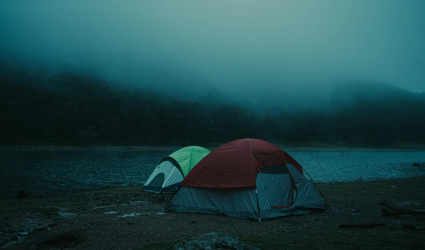 a tent sits on a bank near a body of water