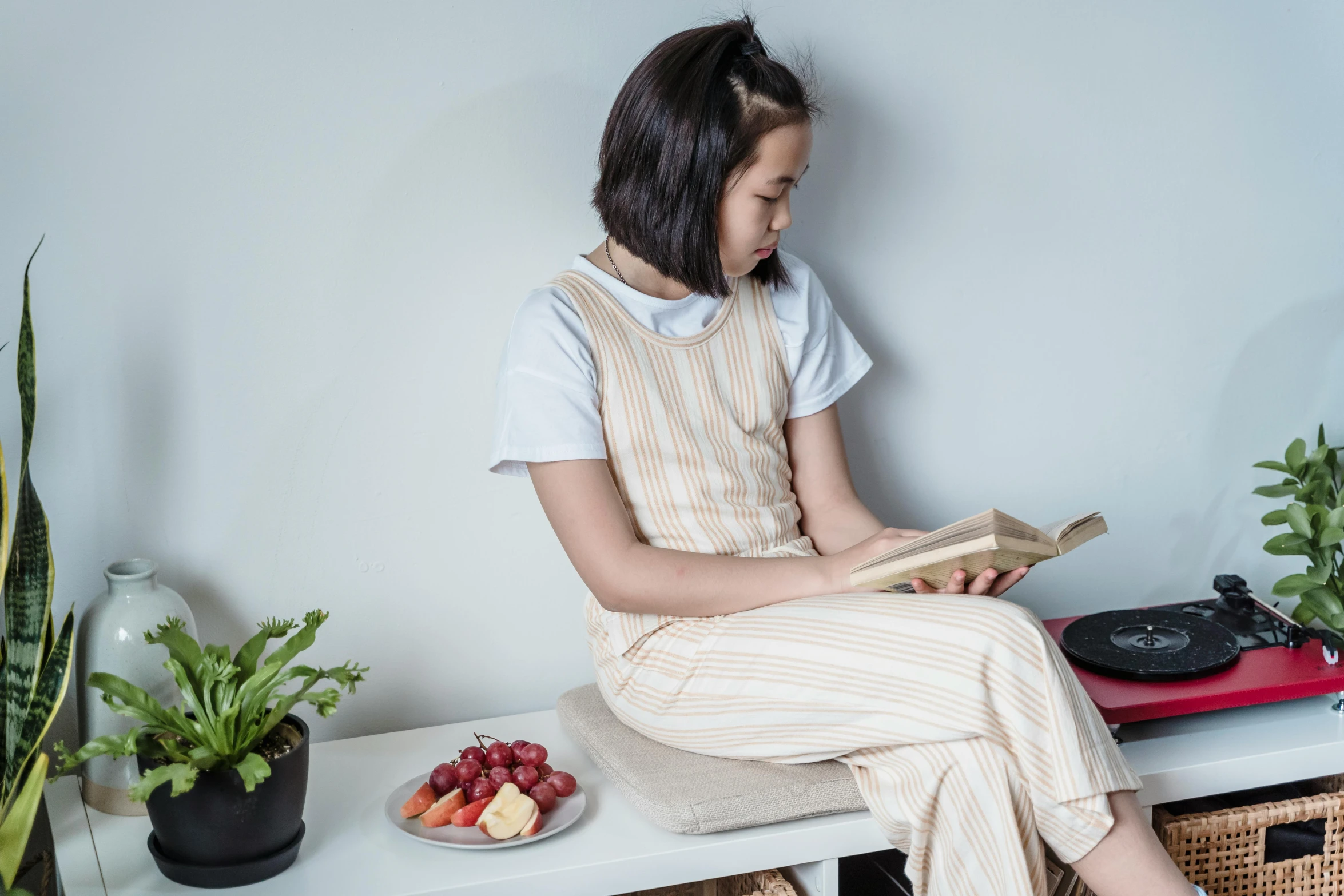 the girl is reading a book while sitting on a table