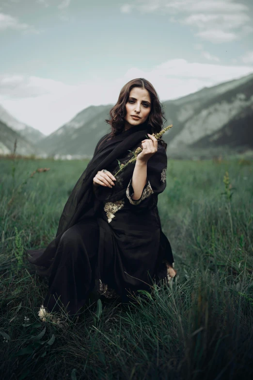 a woman sitting on the grass wearing black clothing