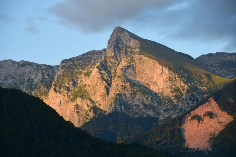 a mountain side in the sun with trees on it