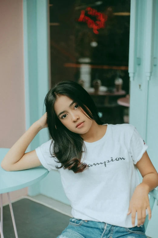 a woman posing in a white t - shirt while sitting outside a building