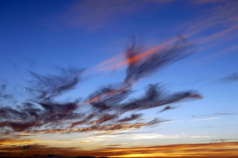 the sun sets behind the clouds above a field