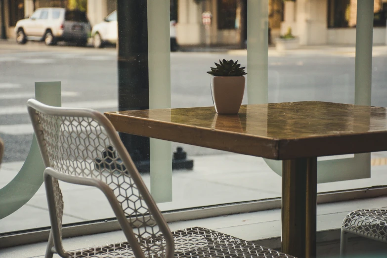 a wooden table with a chair next to a plant