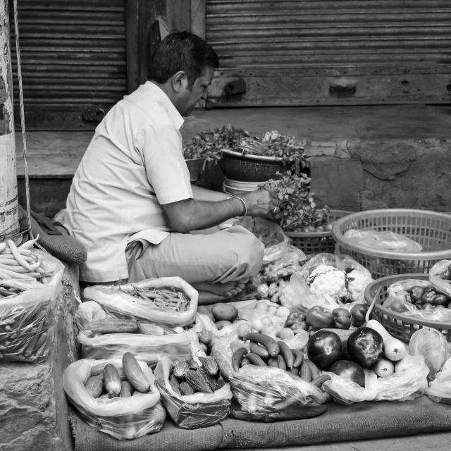 man sitting in front of a selection of fresh vegetables