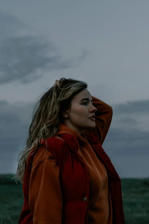 a person with blonde hair standing in front of a cloudy sky