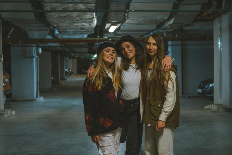 three girls pose for the camera inside an empty building