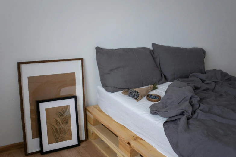 a bed with a wooden frame next to two small framed pictures