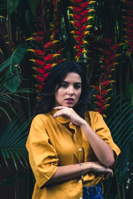 a young woman leaning on her hand with a tropical plant behind her