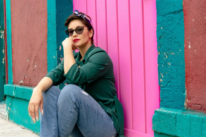 a woman sits outside of colorful building on her phone