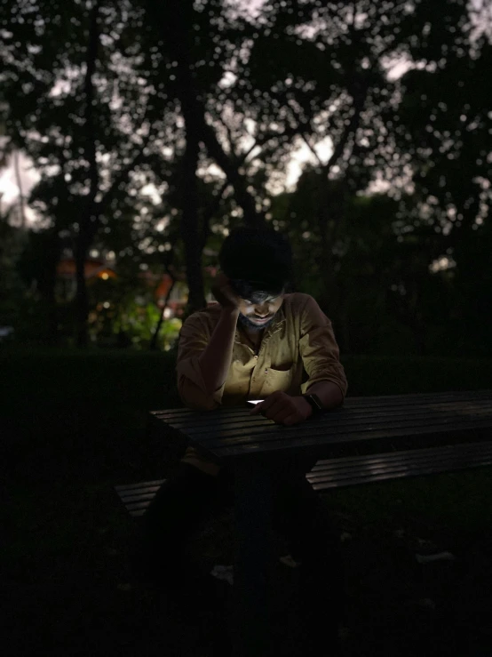 a man with a cell phone sits at a table in the dark