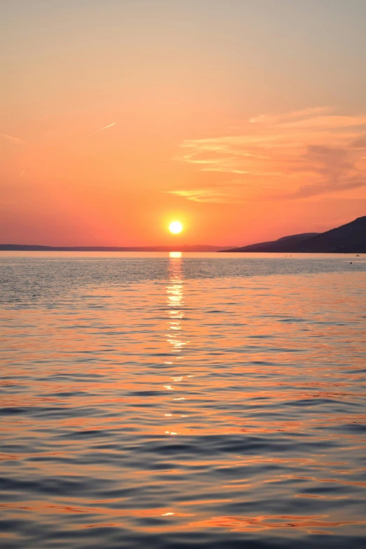 the sun is rising over a lake with two birds sitting on it