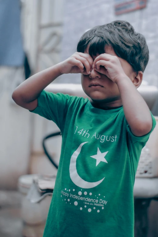 a child with their hands on his face, covering it with his hands