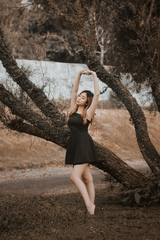 a woman in a short dress poses in front of some trees