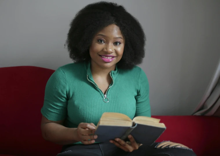 a woman in a green top and black pants holding two books