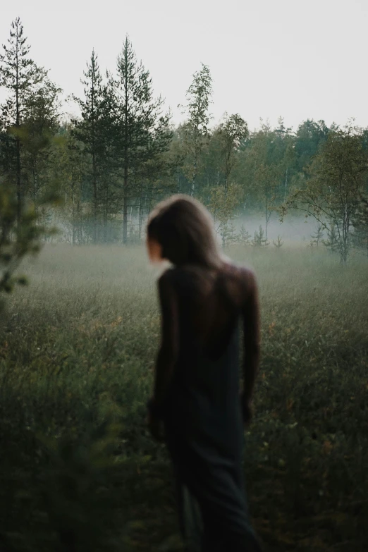 a young woman walks in the fog through a field