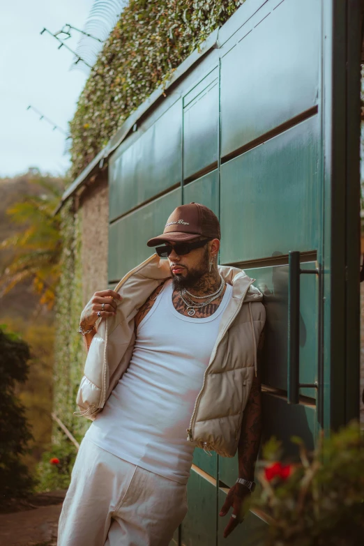 a man with tattoos and a beard leaning on a wall