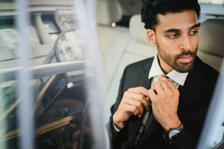 a man that is putting on his tie