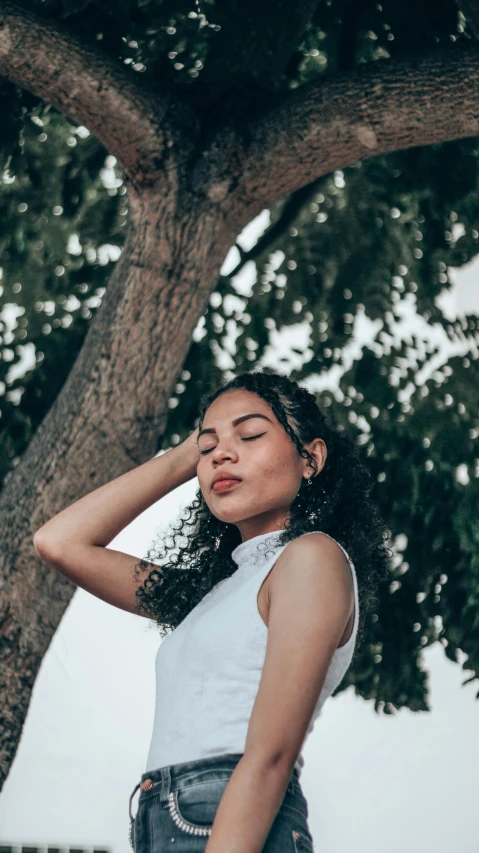 a close up of a woman standing next to a tree