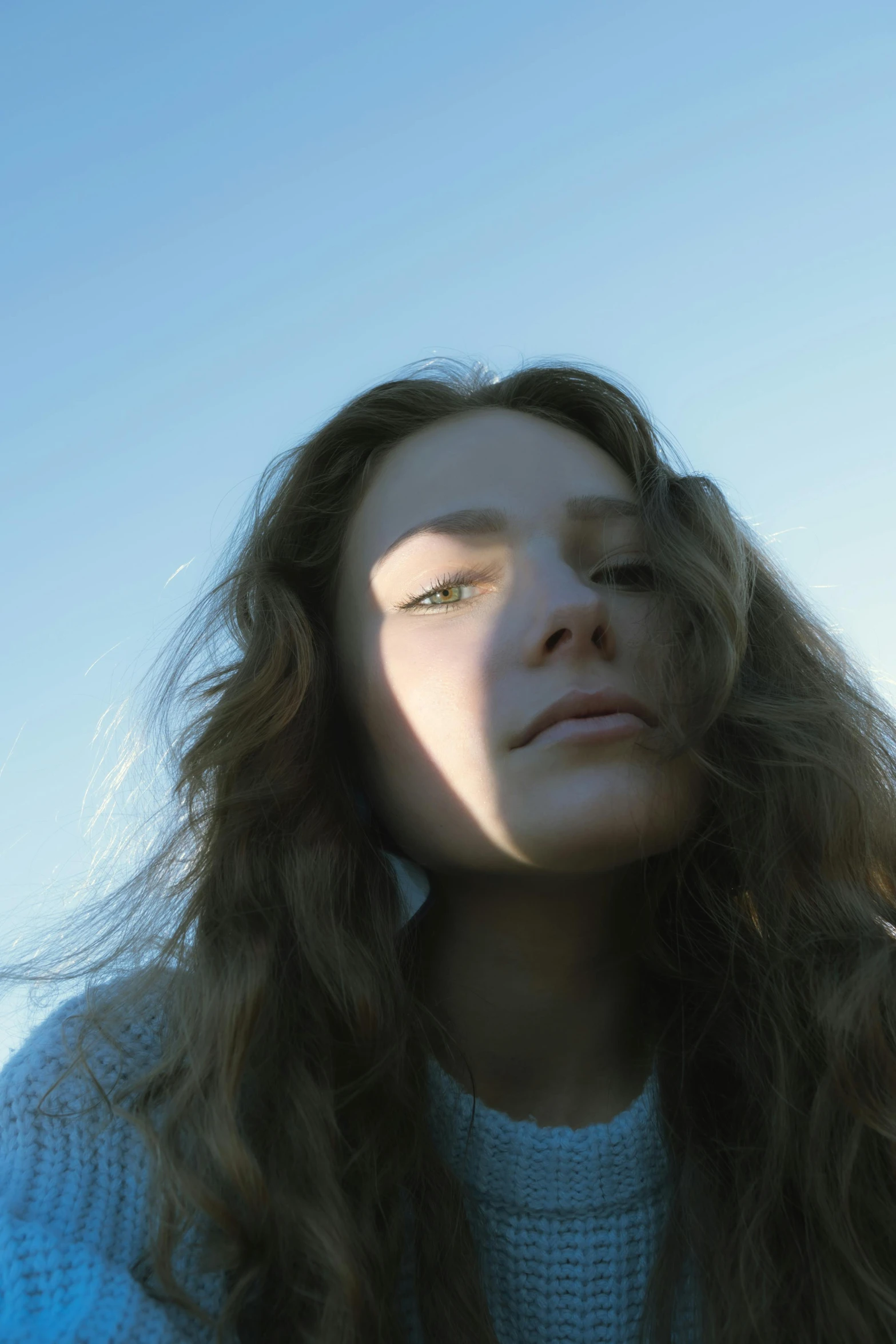 a woman with long brown hair is looking down at the sky