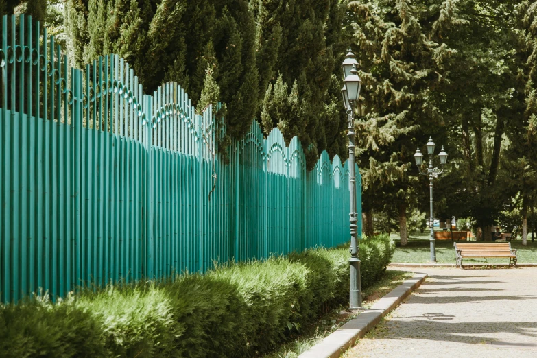 an empty sidewalk next to a green fence