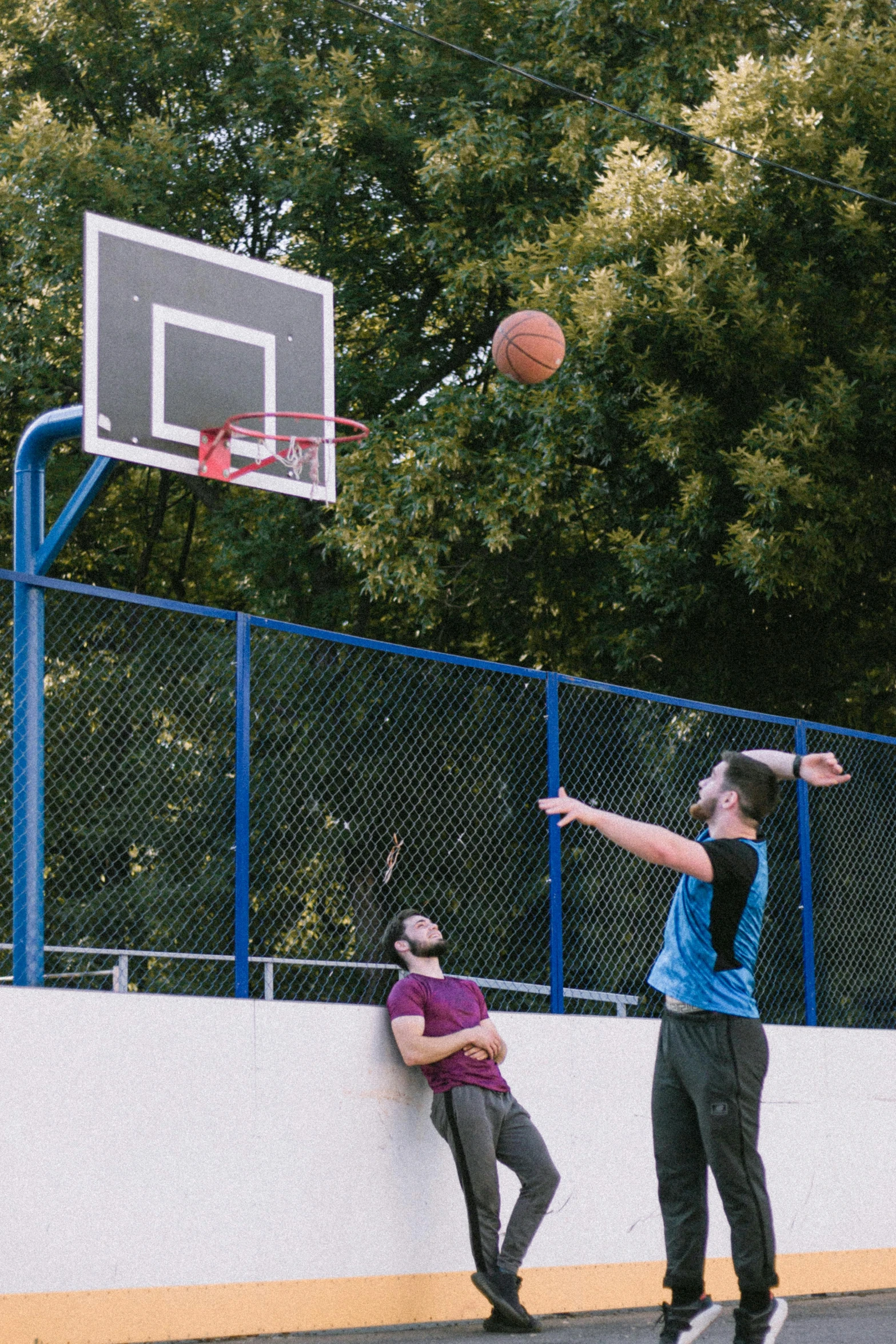 a guy throwing a basketball in front of his friend