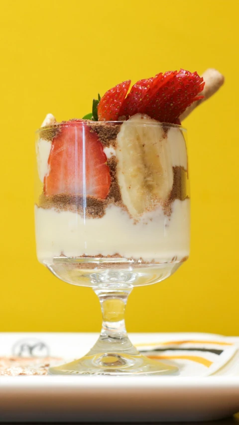 banana split dessert served in small glass, with fruit on top