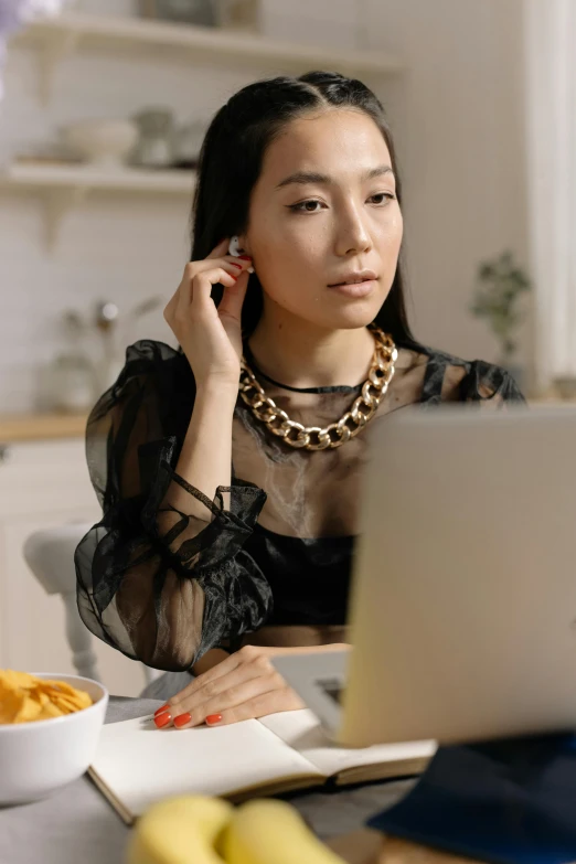 a young woman is talking on a cellphone while looking at her laptop