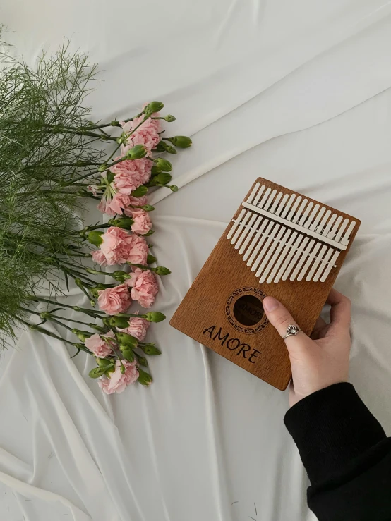 a person's hand holding a book with a flower arrangement in the background