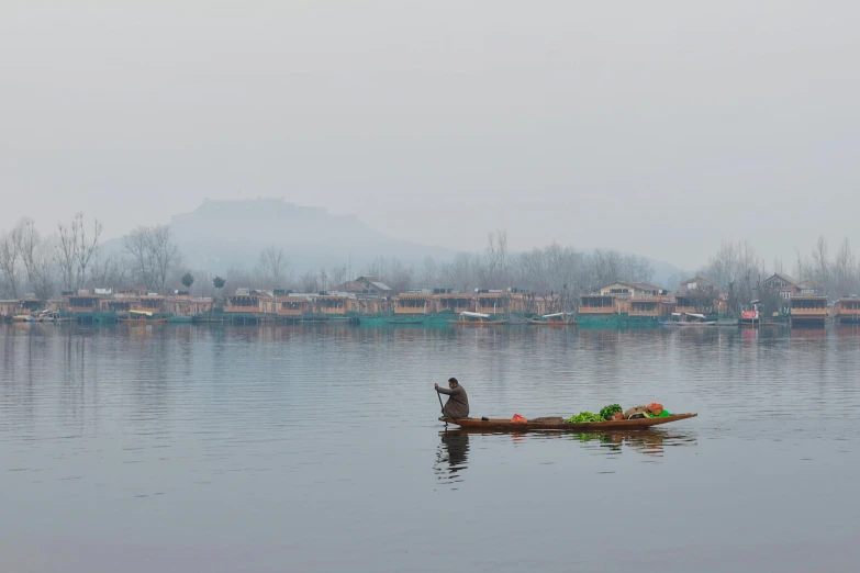 person paddling small boat in the large body of water