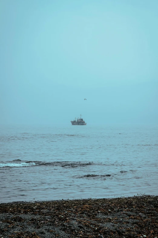 a boat out on the ocean in a light blue fog