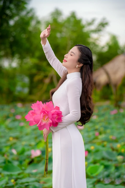 a woman holding flowers near a pond