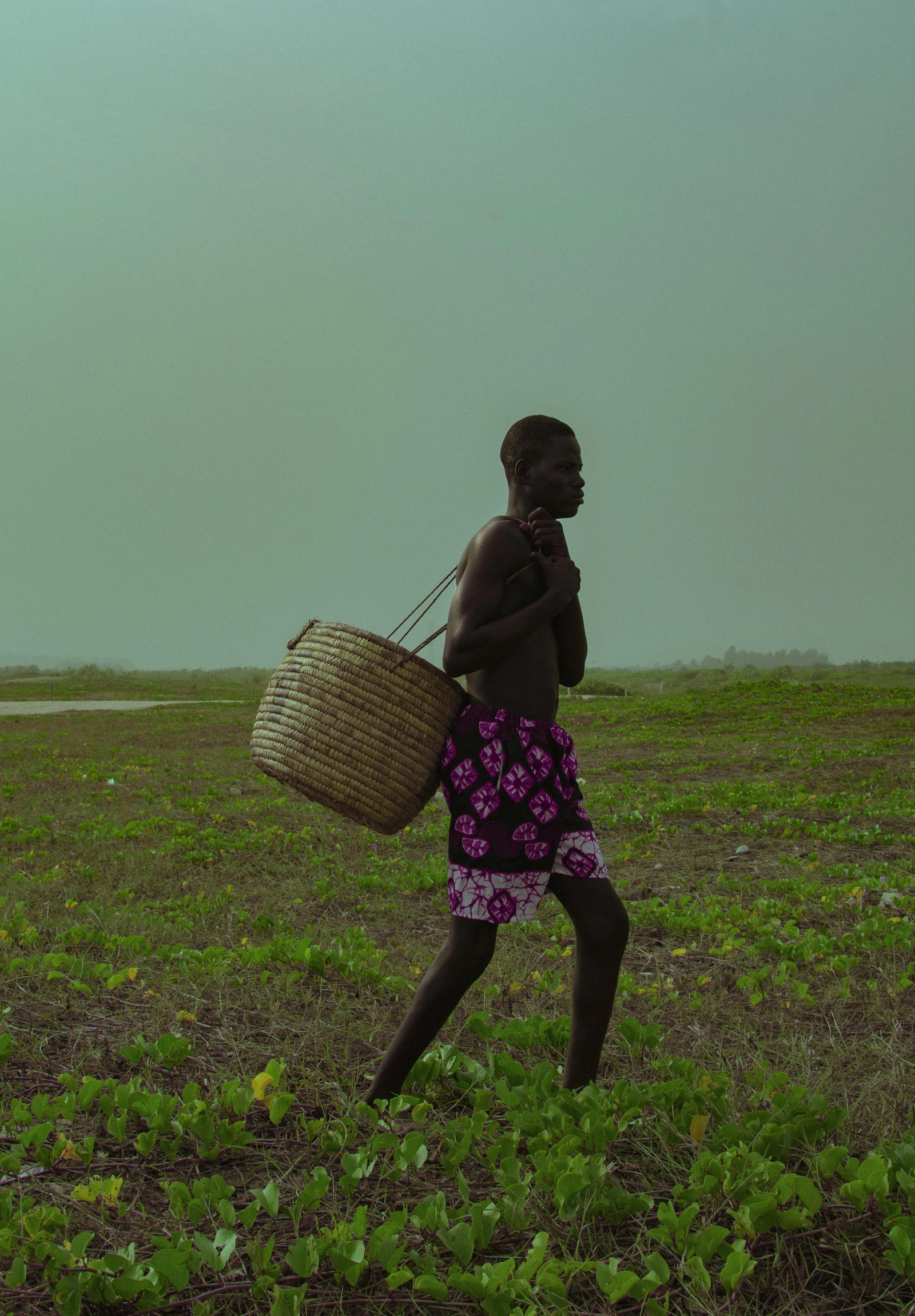 a person walking in a field holding a basket