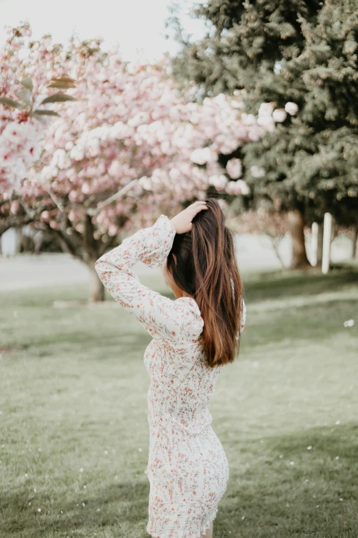 a young woman in a white dress standing by a tree